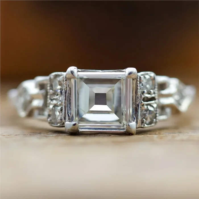Art Deco Step Cut Diamond Set In A Platinum Millgrain Ring With Six Single Cut Diamonds.
